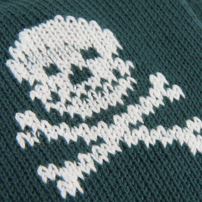 Close-up of a knitted pattern with white yarn on a dark green fabric background