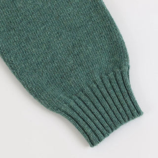 Close-up of a green knitted sleeve on a white background
