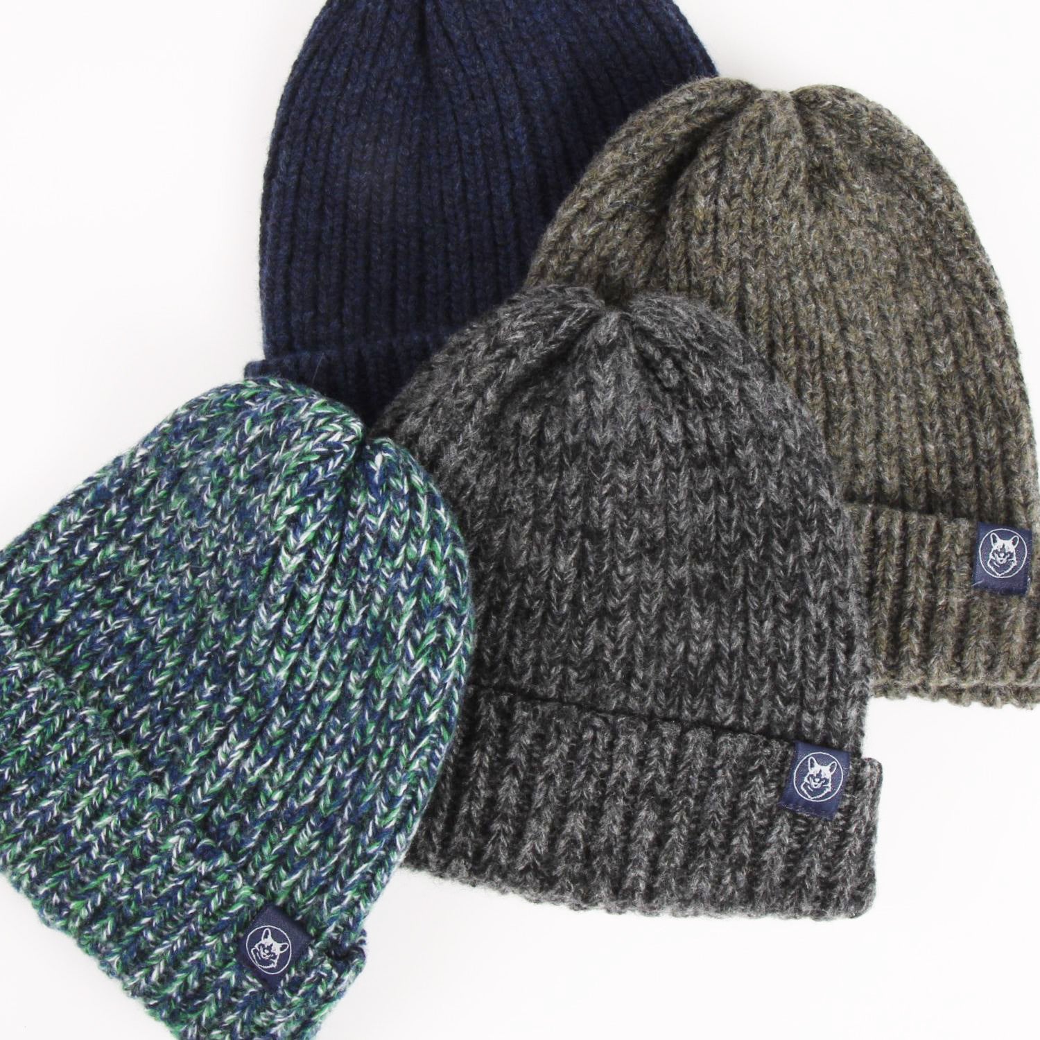 Four knit beanie hats in different colors on a white background