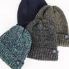 Four knit beanie hats in different colors on a white background