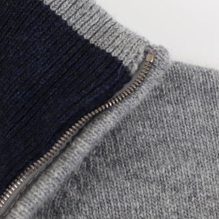 Close-up of a gray and navy zip-up garment on a light gray background