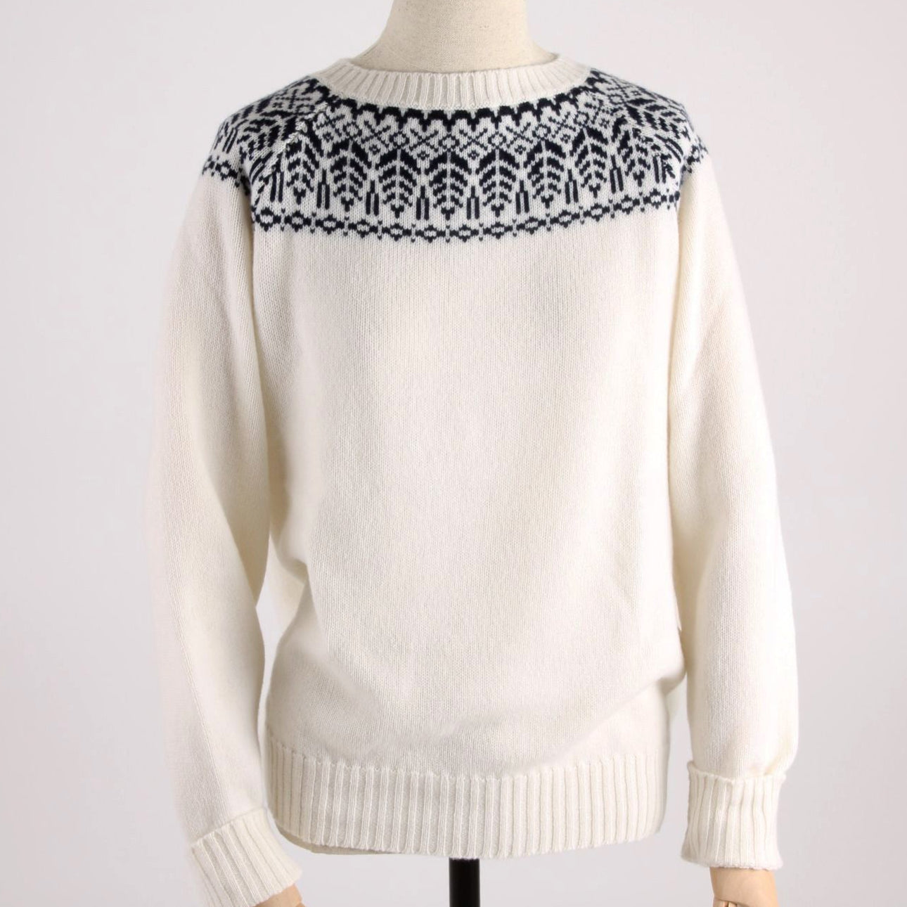 White sweater with navy pattern on neckline on a mannequin against a white background