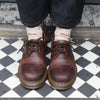 Brown leather shoes worn with dark jeans and white socks with corgi dog all over pattern on a checkered floor.