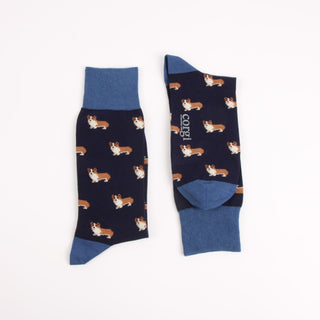 Pair of navy socks with an all over corgi dog logo and brighter blue top, heel and toe photographed on a white background