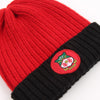 Red and black knit beanie with a logo patch on a white background