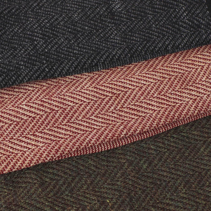 Close-up of a textured fabric with a herringbone pattern, featuring a dark gray and red color scheme.