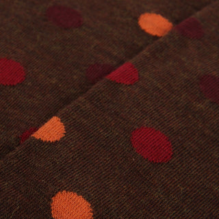 Close-up of brown sock fabric with red and orange polka dots