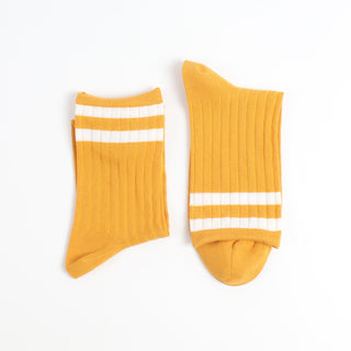 Pair of yellow socks with two finer white stripes on the top section of the sock photographed on a white background