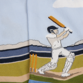 Knitted sock with a cricket player design on a light blue background