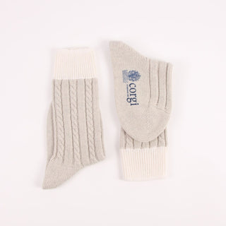 Pair of silver socks with cable knit pattern on a white background