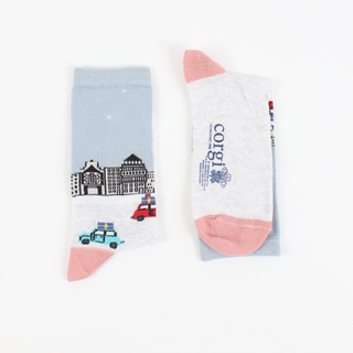 A pair of women's socks with a Christmas in the city scene design, featuring a snow-covered street, buildings, and decorative elements.