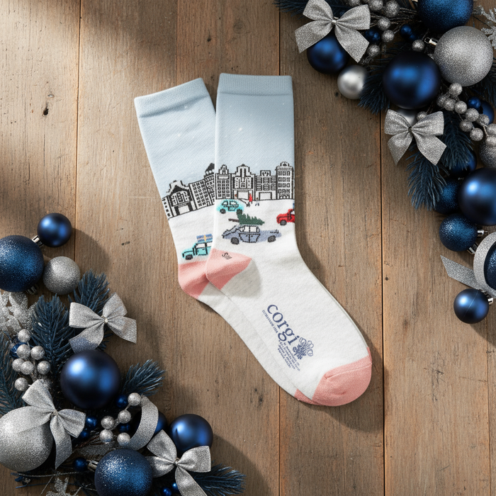 A pair of women's socks with a Christmas in the city scene design, featuring a snow-covered street, buildings, and decorative elements.
