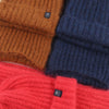 Stack of brown, blue, and red knitted sweaters with brand logos.