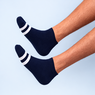 Navy socks with white stripes worn by a person on a light blue background
