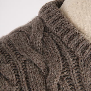 Close-up of a brown knitted sweater on a mannequin against a white background
