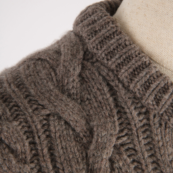 Close-up of a brown knitted sweater on a mannequin against a white background