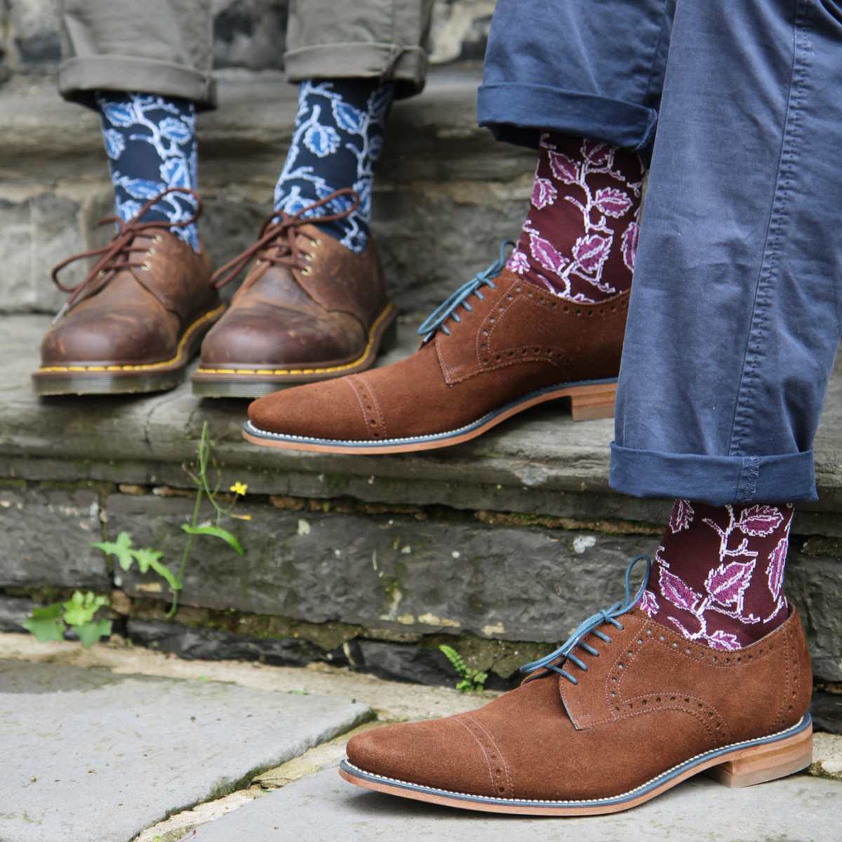 brown leather dress shoes worn with patterned socks and cuffed pants, standing on rustic stone steps outdoors.