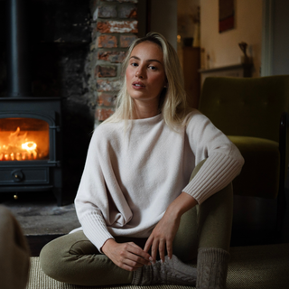 Woman sitting in a cozy living room with a fireplace