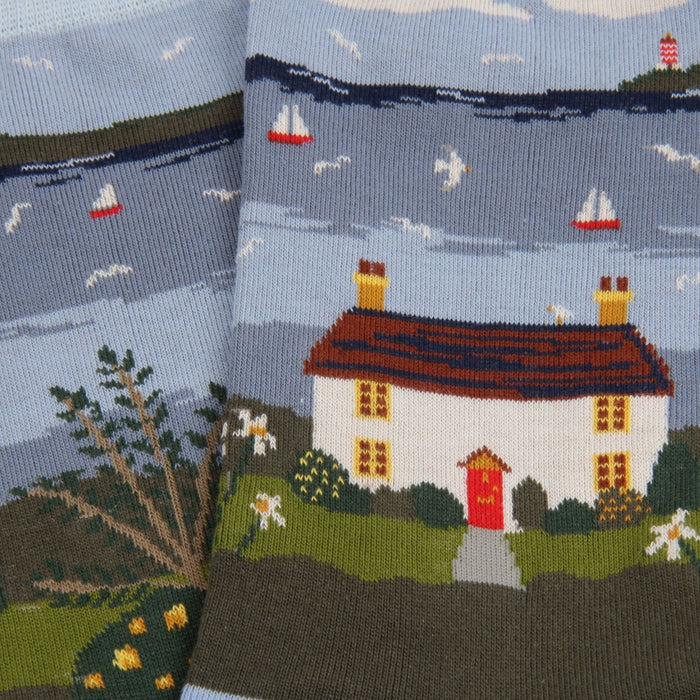 Socks with a scenic design of a house, trees, and boats on a blue sky background.