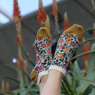 person wearing floral trainer socks with foliage in the background