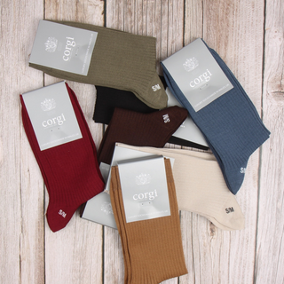 Assorted pairs of socks with 'corgi' branding on a wooden surface