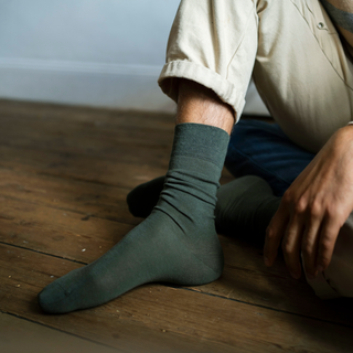 Person wearing green socks sitting on a wooden floor.