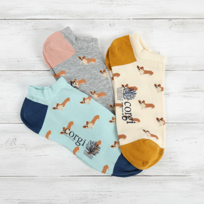Four pairs of socks with corgi patterns on a wooden surface