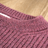 Close-up of a textured pink knitted fabric on a wooden surface