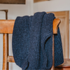 Blue knitted sweater draped over a wooden chair indoors