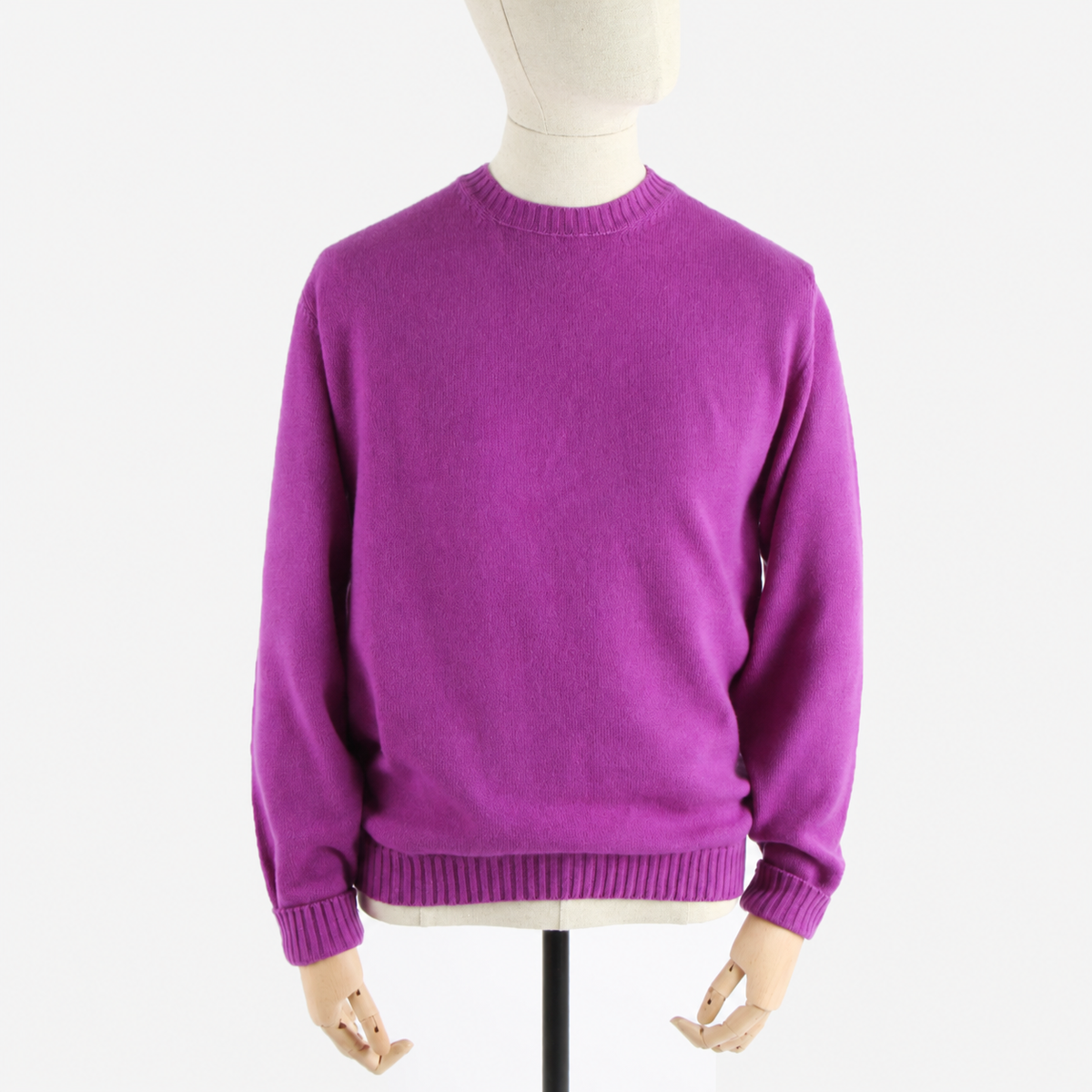 A vibrant purple knit crewneck sweater displayed on a cream-colored mannequin torso with wooden hands, set against a plain white background.