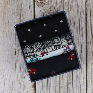 three pairs of men's socks with a Christmas-themed design, including a cityscape.