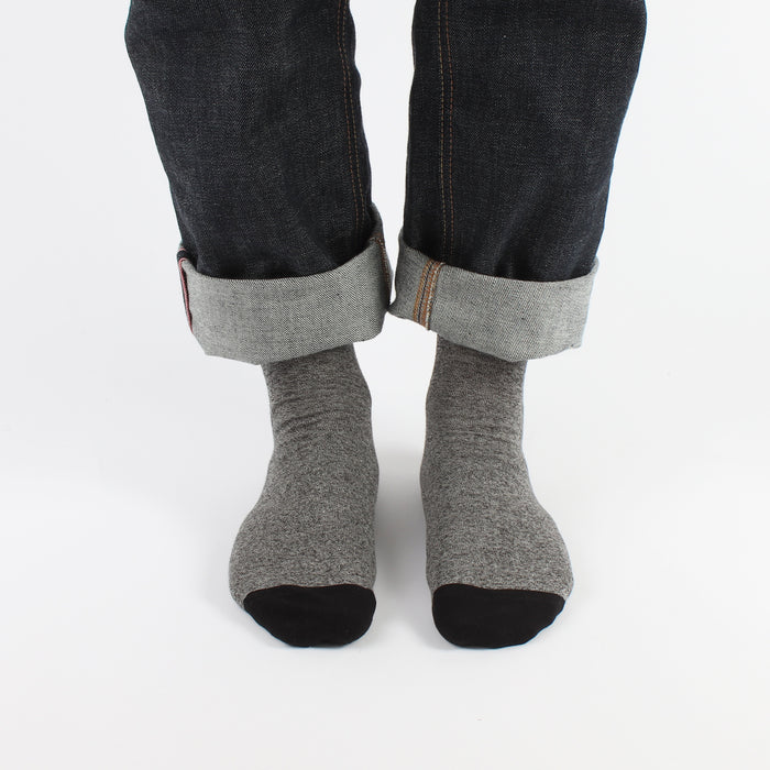 Gray socks worn with dark jeans on a white background