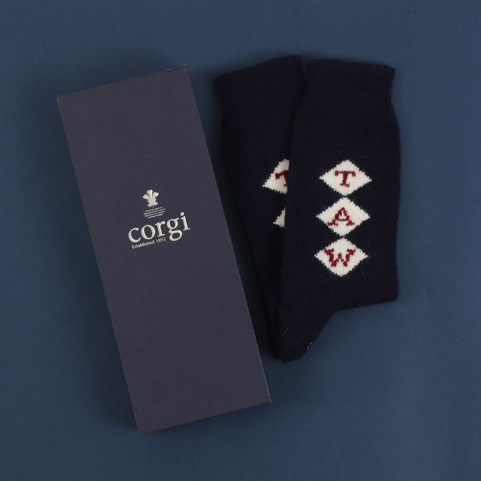 A pair of navy blue cashmere socks with a monogram pattern, showing the socks' texture and the brand name 'Corgi'.