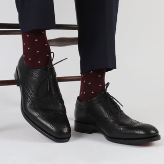 Maroon socks with white polka dots worn with a pair of smart black shoes