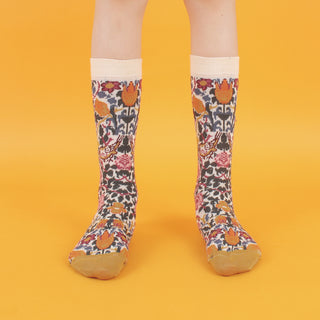 A pair of patterned cotton socks featuring a floral design with roses and leaves, and gold accents on the heel and toe, displayed against a yellow background.