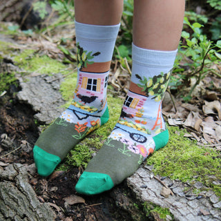 Colourful socks with cottage spring garden design worn outdoors on a log