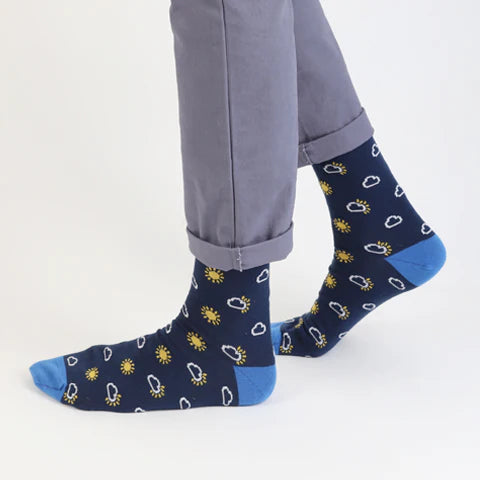 Person wearing navy socks with yellow and white sun/cloud patterns all over
