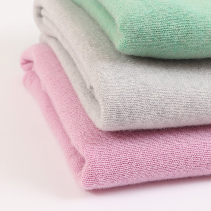 Stack of folded pastel-colored ponchos on a light background