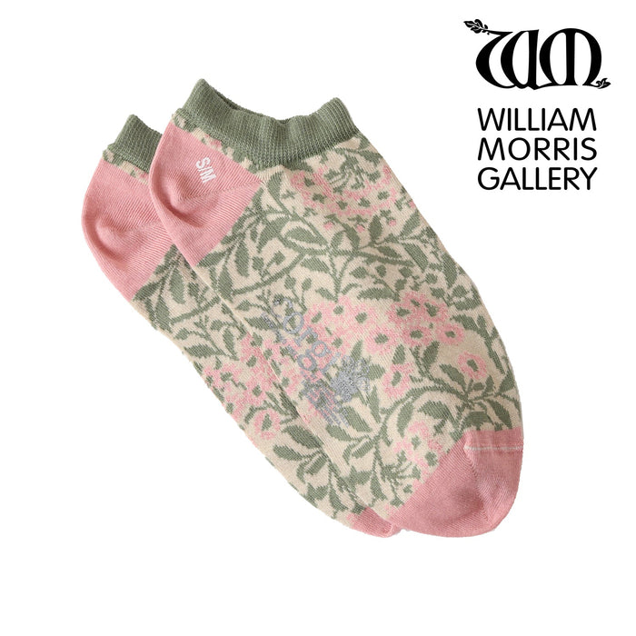 A pair of pink trainer socks with a green floral pattern, displayed in a vertical split view of a person's feet.