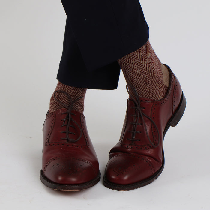 A pair of men's formal herringbone merino wool socks in a neutral color, worn with dress shoes.