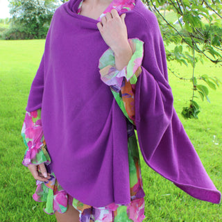 Person wearing a purple poncho with colorful sleeves in an outdoor setting