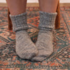 Gray socks worn on a patterned rug
