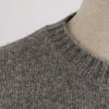 Close-up of a gray knitted sweater collar on a neutral background