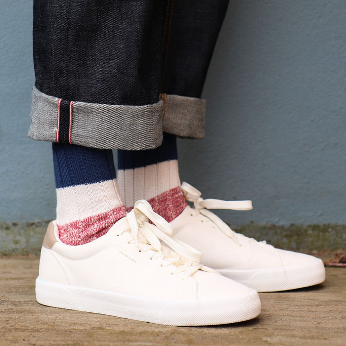 man wearing striped cotton socks against a blue wall 