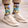 Colourful geometric-patterned sock worn with trainers.