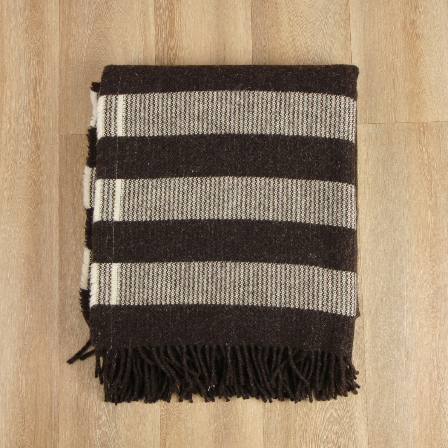 Striped blanket with black and gray stripes on a wooden surface