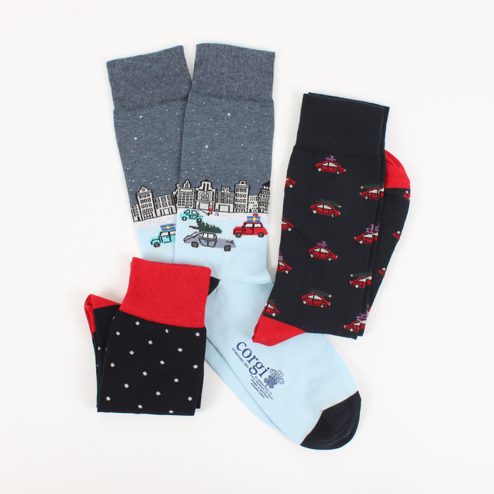 three pairs of men's socks with a Christmas-themed design, including a cityscape. 