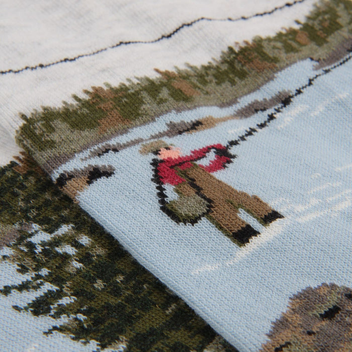 knitted design of a person in a red top and hat standing in the river fishing 