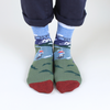 Person wearing socks with a design of a cyclist in the mountains on the open road, photographed on a white background.