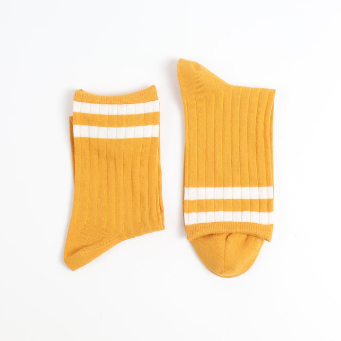 Pair of yellow socks with two finer white stripes on the top section of the sock photographed on a white background